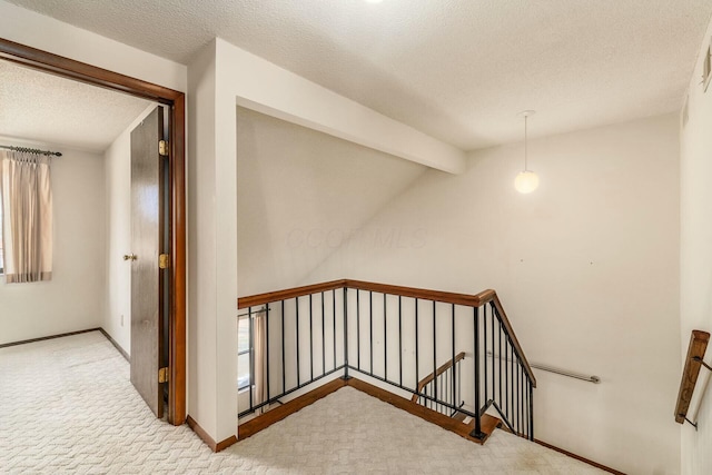 staircase featuring lofted ceiling with beams, carpet, and a textured ceiling