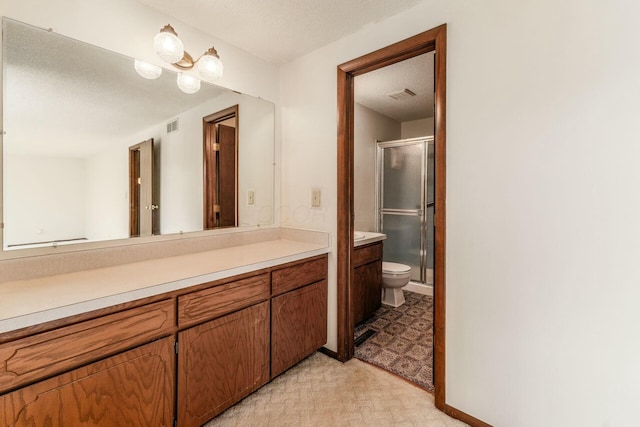 bathroom featuring vanity, a textured ceiling, a shower with door, and toilet