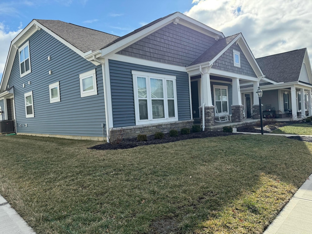 craftsman inspired home with a porch, central AC unit, and a front lawn