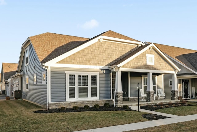 craftsman house featuring a porch, central AC unit, and a front lawn