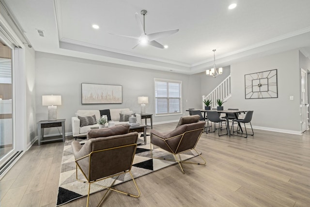 living room featuring crown molding, a raised ceiling, and light wood-type flooring