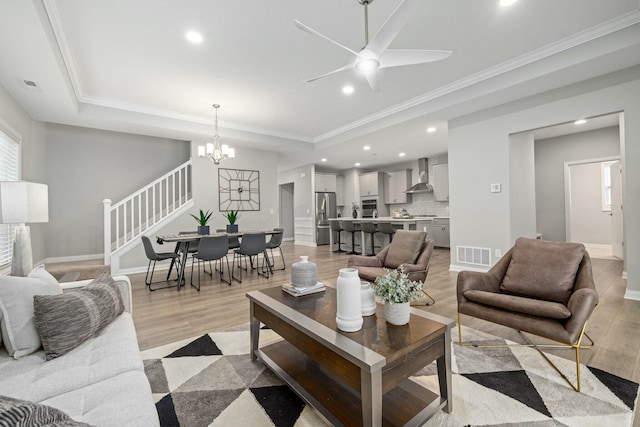 living room with crown molding, a tray ceiling, and light hardwood / wood-style floors