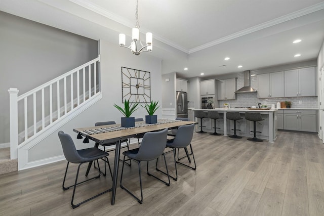 dining room with a notable chandelier, light hardwood / wood-style flooring, and ornamental molding