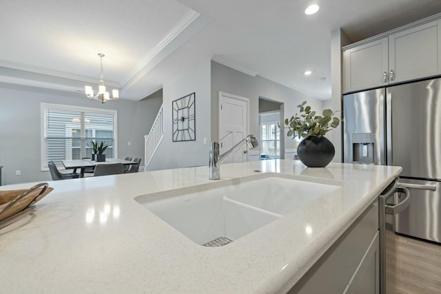 kitchen featuring decorative light fixtures, sink, gray cabinetry, stainless steel fridge, and light stone counters