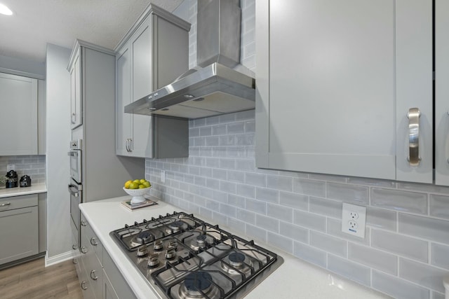 kitchen featuring gas cooktop, gray cabinetry, backsplash, range hood, and dark hardwood / wood-style flooring