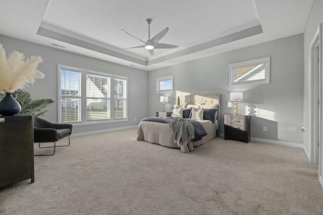 bedroom with a tray ceiling, light colored carpet, and ceiling fan