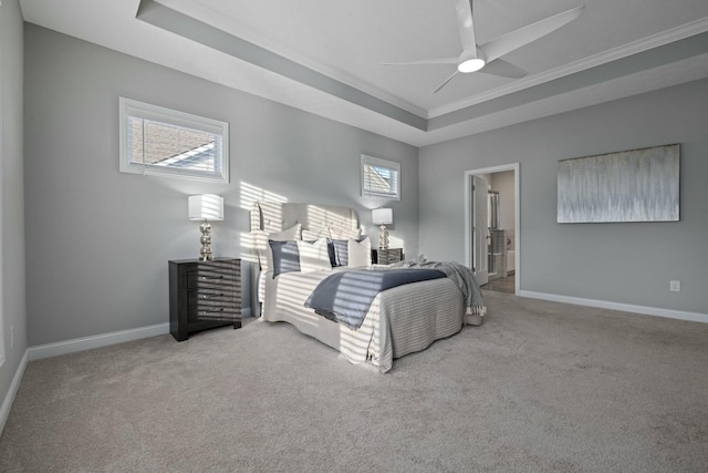 bedroom with light carpet, connected bathroom, a tray ceiling, and multiple windows