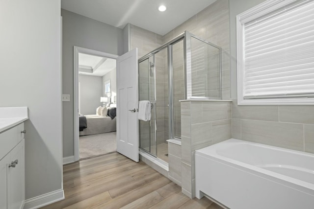 bathroom with independent shower and bath, wood-type flooring, a wealth of natural light, and vanity