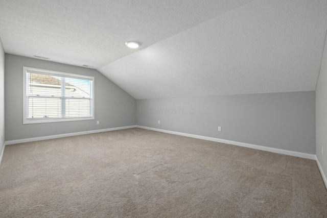 bonus room with carpet floors, vaulted ceiling, and a textured ceiling