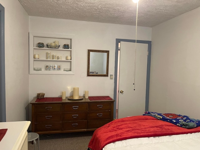 bedroom with a textured ceiling and dark carpet