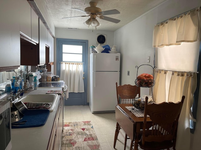 kitchen with white refrigerator, ceiling fan, a textured ceiling, and light tile patterned floors