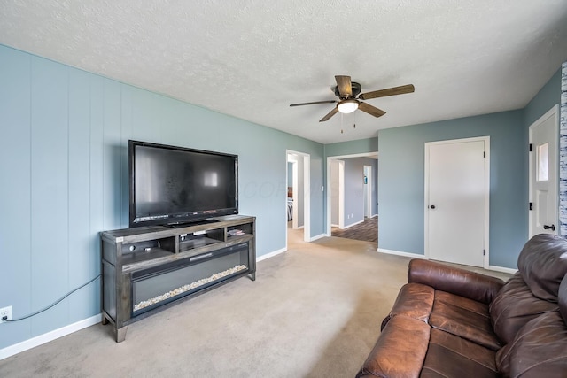 carpeted living room featuring ceiling fan and a textured ceiling