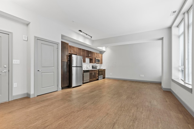 unfurnished living room with sink, light hardwood / wood-style floors, and a healthy amount of sunlight