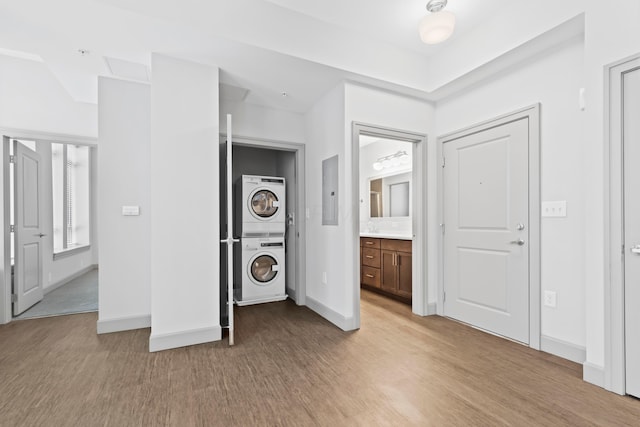 unfurnished bedroom featuring connected bathroom, stacked washer and dryer, and light wood-type flooring