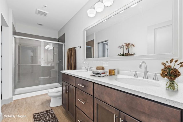 bathroom featuring vanity, hardwood / wood-style floors, a shower with shower door, and toilet