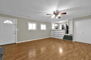 foyer entrance featuring wood-type flooring, ornamental molding, and ceiling fan