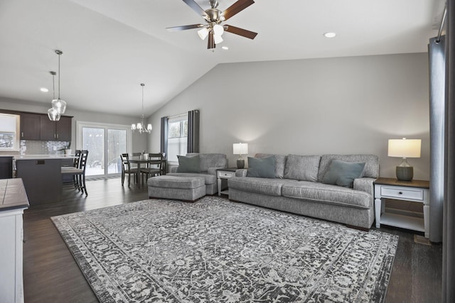 living room with ceiling fan with notable chandelier, dark hardwood / wood-style floors, and vaulted ceiling