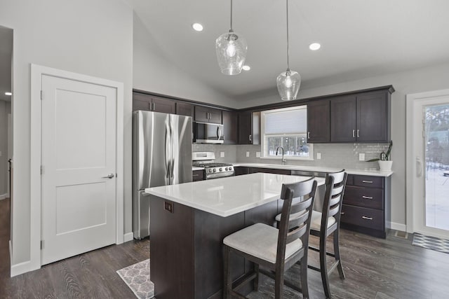 kitchen with lofted ceiling, sink, a kitchen island, pendant lighting, and stainless steel appliances