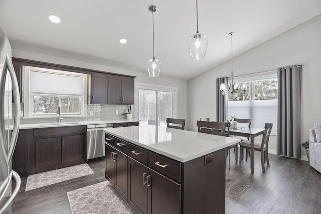 kitchen featuring sink, vaulted ceiling, appliances with stainless steel finishes, a kitchen island, and pendant lighting