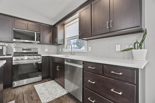 kitchen featuring sink, dark wood-type flooring, appliances with stainless steel finishes, dark brown cabinets, and vaulted ceiling