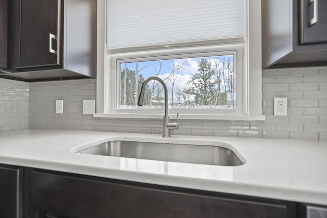 kitchen with dark brown cabinetry, sink, and tasteful backsplash