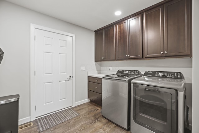 clothes washing area featuring cabinets, dark hardwood / wood-style floors, and independent washer and dryer