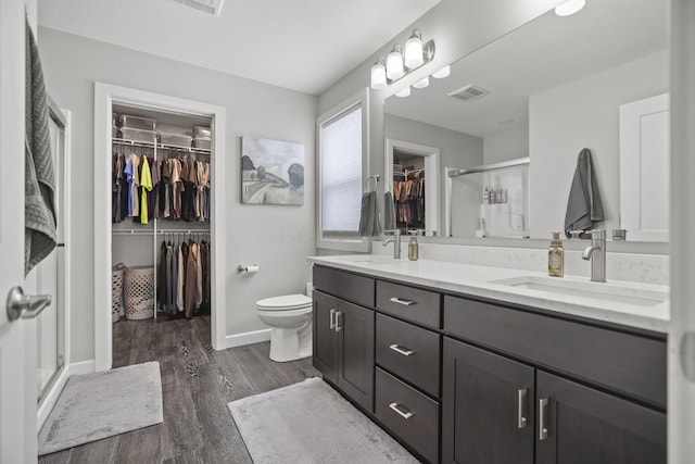 bathroom featuring toilet, hardwood / wood-style floors, vanity, and a shower with shower door