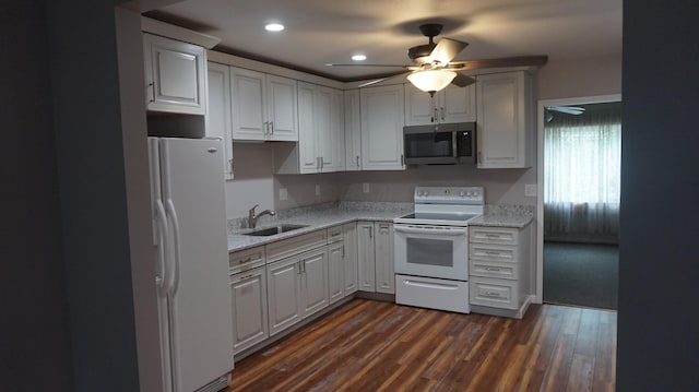 kitchen with sink, white appliances, dark wood-type flooring, light stone countertops, and white cabinets