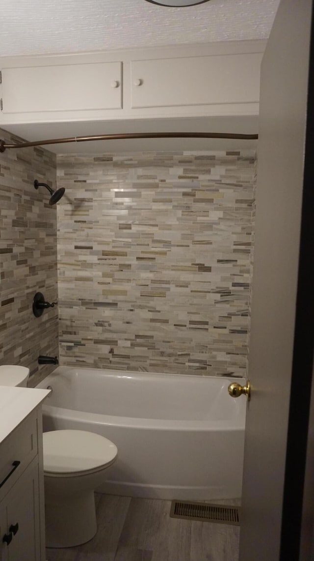 full bathroom featuring tiled shower / bath, vanity, toilet, and hardwood / wood-style floors