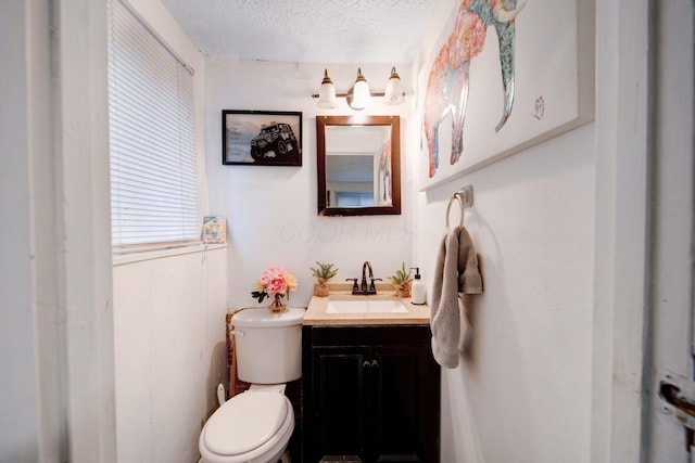 bathroom with vanity, toilet, and a textured ceiling