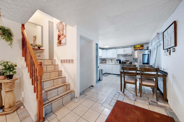 kitchen with white cabinetry, stainless steel appliances, a textured ceiling, and light tile patterned floors