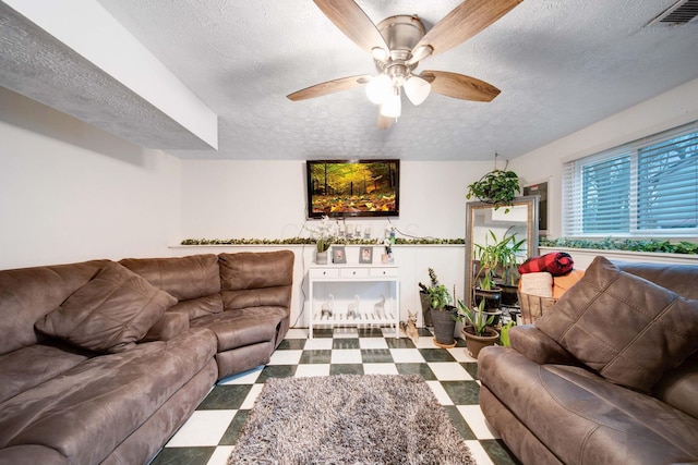 living room with ceiling fan and a textured ceiling