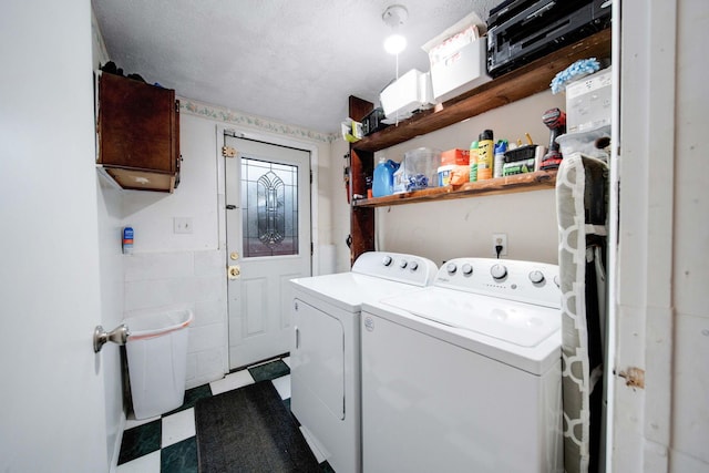 washroom with tile walls, a textured ceiling, and washing machine and clothes dryer