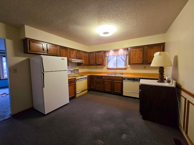 kitchen with dark carpet, white appliances, sink, and a textured ceiling