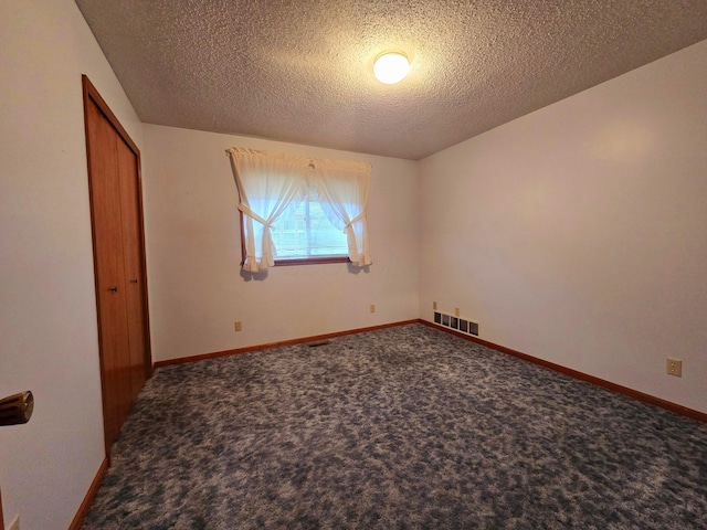 carpeted empty room with a textured ceiling