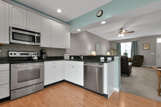 kitchen featuring stainless steel appliances, white cabinets, backsplash, and kitchen peninsula