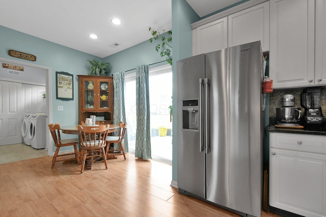 kitchen with white cabinets, high end fridge, washing machine and clothes dryer, and light wood-type flooring