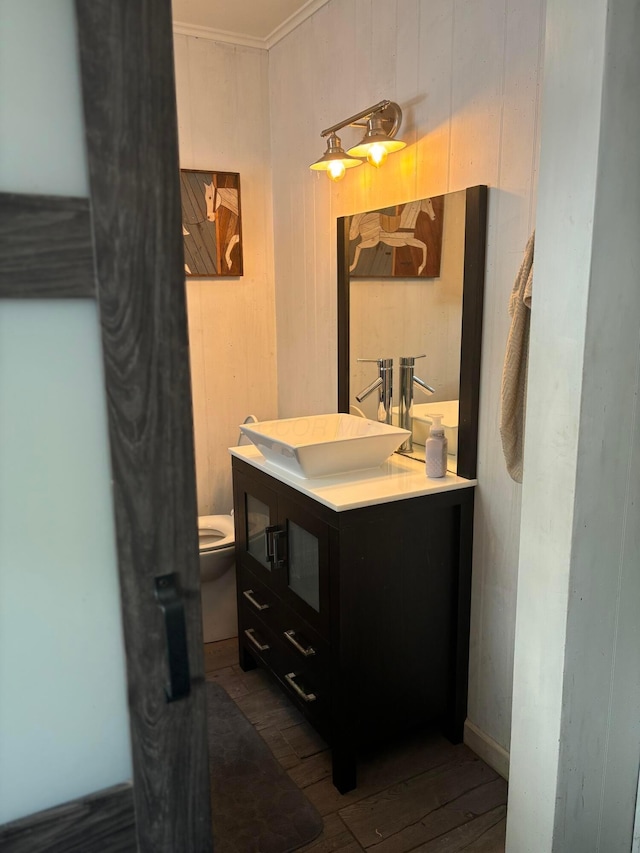 bathroom featuring vanity, hardwood / wood-style floors, wooden walls, and toilet