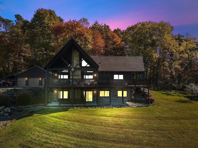 back house at dusk with a garage, an outdoor structure, and a lawn