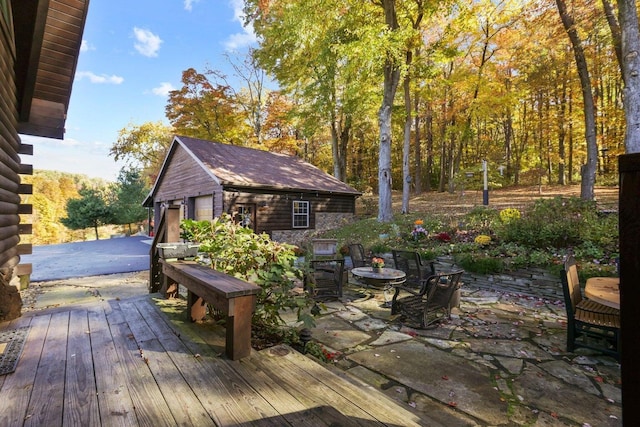 deck with a garage, an outdoor structure, and a patio area