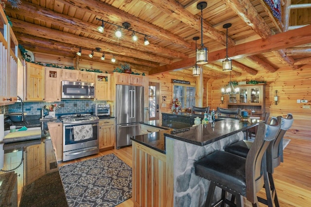 kitchen with a center island, light brown cabinets, pendant lighting, stainless steel appliances, and light hardwood / wood-style floors