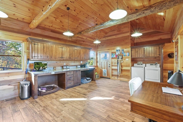 kitchen featuring pendant lighting, light hardwood / wood-style floors, washing machine and clothes dryer, and wood walls