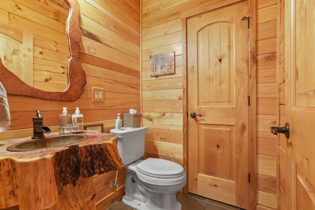 bathroom featuring vanity, toilet, tile patterned flooring, and wood walls