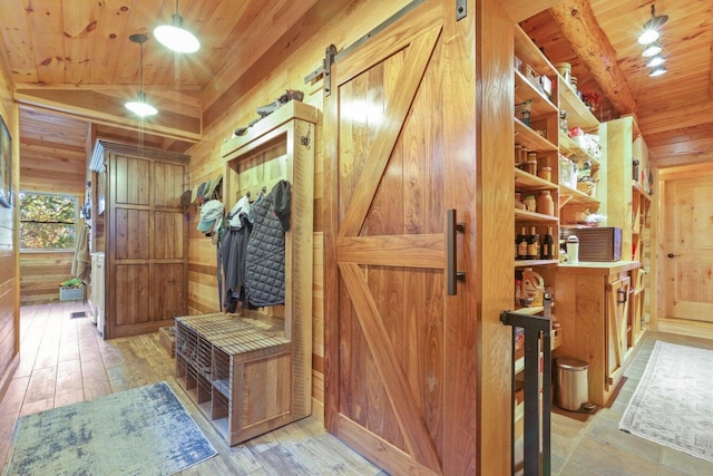 mudroom featuring vaulted ceiling, wood walls, light hardwood / wood-style floors, wood ceiling, and a barn door