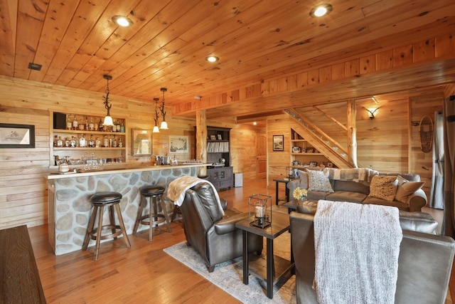 living room with bar, wood ceiling, wooden walls, and light hardwood / wood-style floors