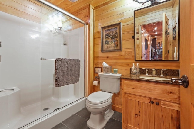 bathroom featuring a shower with door, wooden walls, vanity, tile patterned floors, and toilet