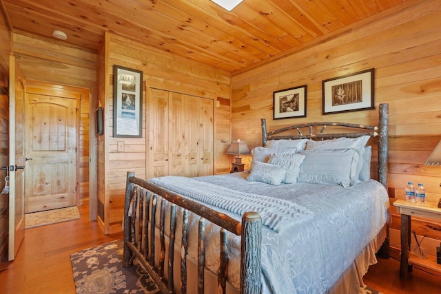 bedroom featuring hardwood / wood-style flooring, wooden walls, wood ceiling, and a closet