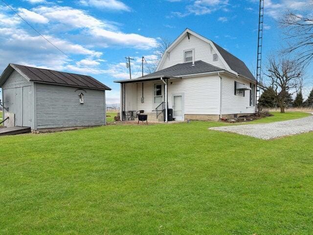 rear view of house with a shed and a lawn