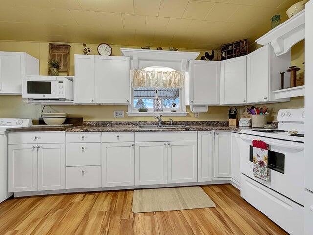 kitchen featuring white cabinetry, sink, and white appliances