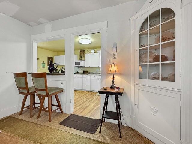 bar featuring white cabinetry and light wood-type flooring